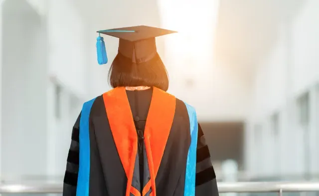 PhD student with their back facing viewer wearing an orange nursing hood